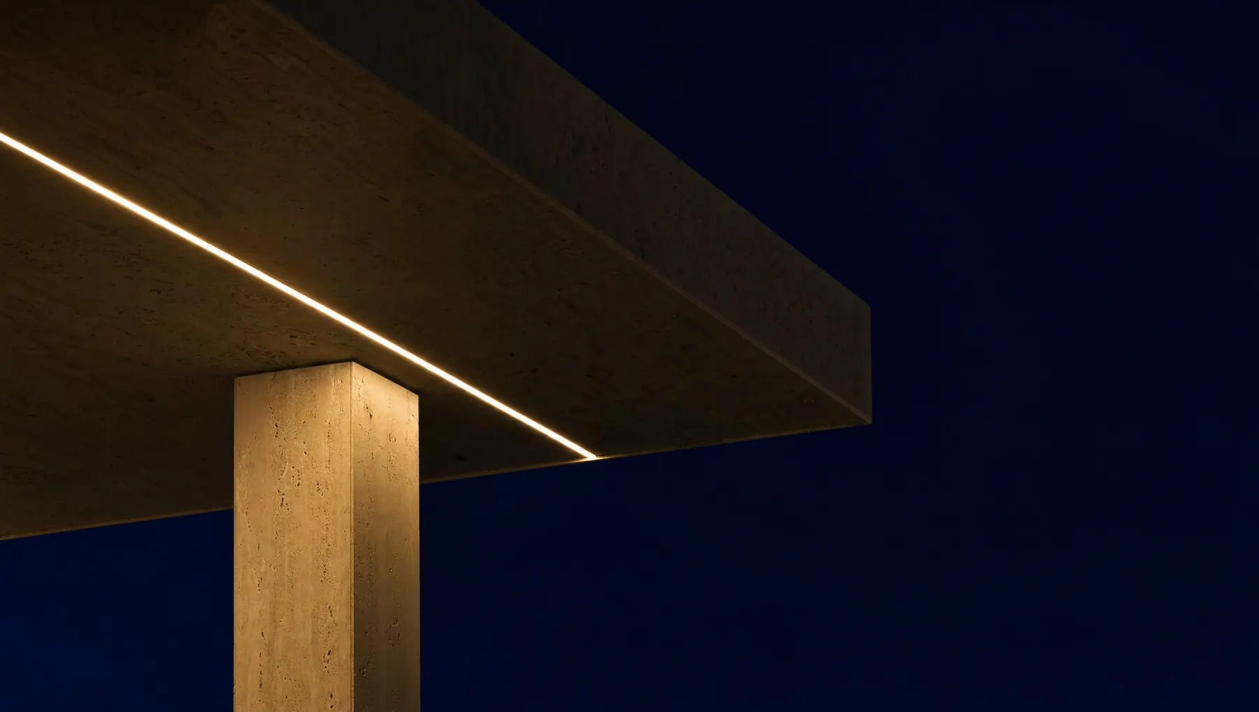 A deep cantilevered roof edge at night with a thin line of warm light running beneath it, beside a fluted walnut door with a brass handle.