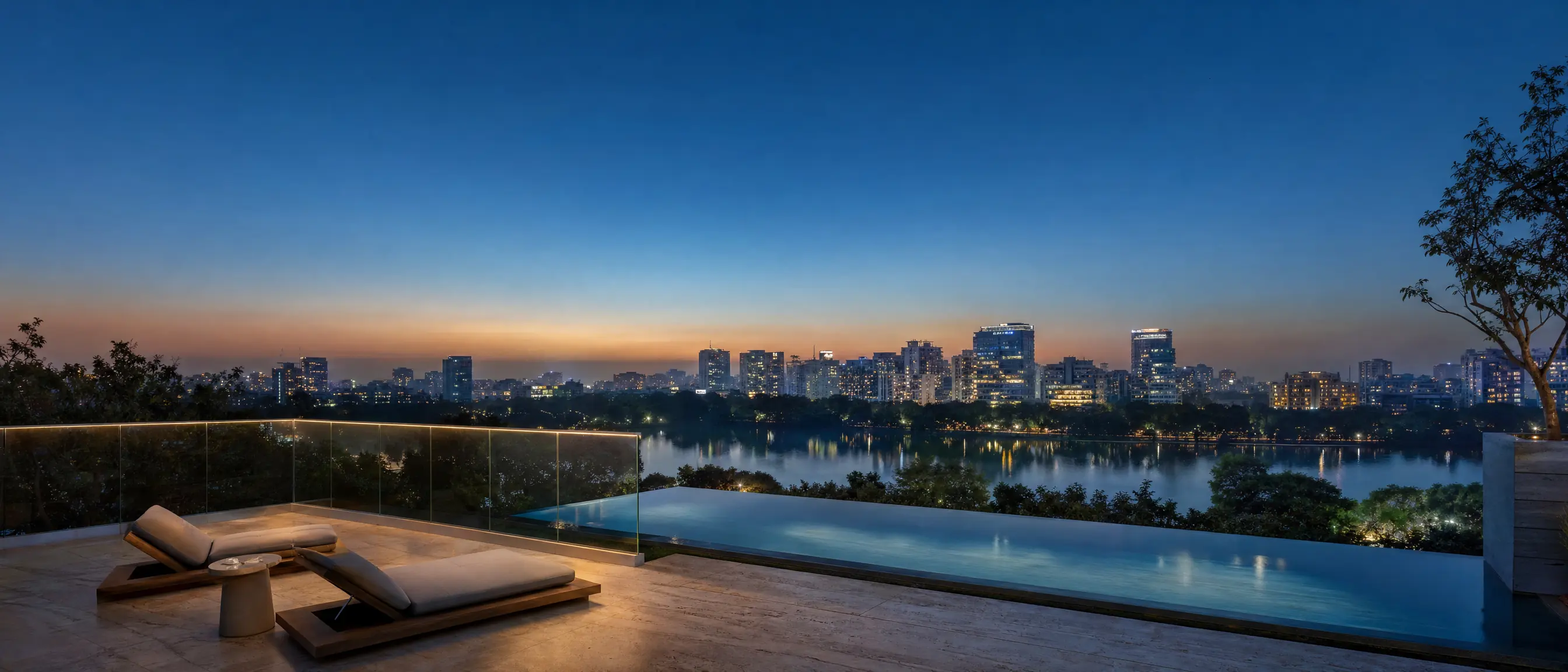 A rooftop terrace with lounge chairs and a plunge pool at blue hour, overlooking Gulshan Lake and the lights of the Dhaka skyline.