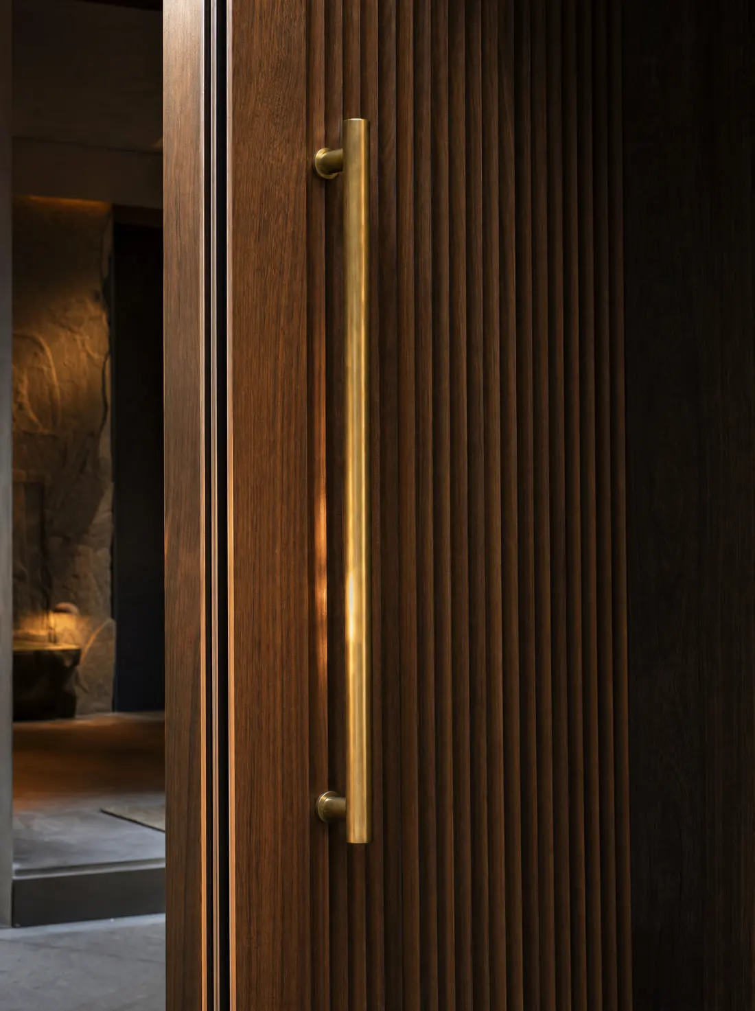 A fluted walnut door with a long brushed-brass handle.